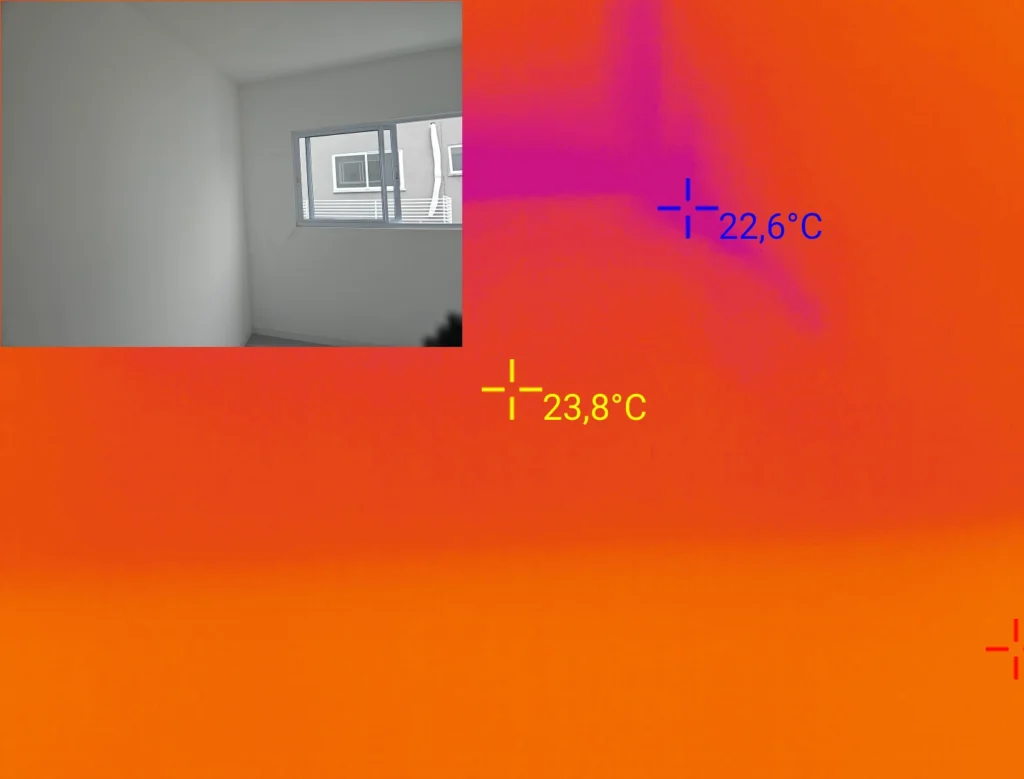 Imagem termográfica de esquadria com fissuras nos cantos a 45°, apresentando redução de temperatura superficial e indícios compatíveis com infiltração pela fachada.
